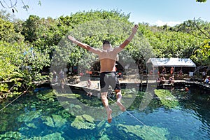 Man jumps off a cliff into the Cristalino cenote in Mexico. photo