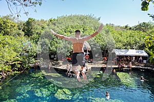 Man jumps off a cliff into the Cristalino cenote in Mexico. photo