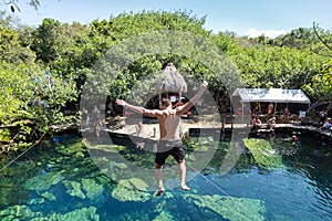 Man jumps off a cliff into the Cristalino cenote in Mexico. photo