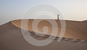 Man in kandura in a desert praying