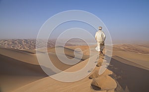 Man in kandura in a desert at sunrise