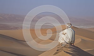 Man in kandura in a desert at sunrise