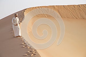 Man in kandura in a desert at sunrise