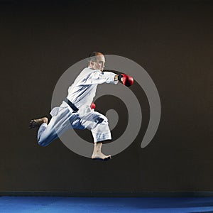 A man in karategi strikes with a hand in a jump