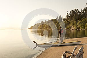 Man with kayak on beach looking out at water. Solo outdoor adventure sports sea kayaking in beautiful, remote nature wilderness