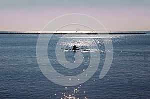 Man on a kayak in the blue sea at sunrise in Italy