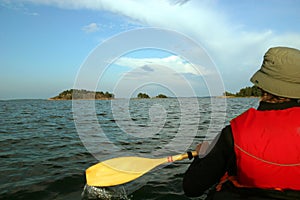 Man in a kayak paddling toward an island, Scandinavia