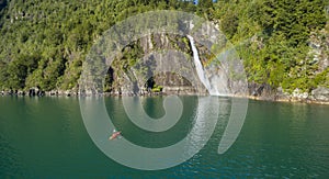 Man in kayak paddling towards the waterfall photo