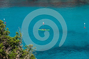 Man on a kayak in the sea of En Porter cove in Menorca
