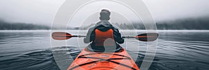 Man kayaking on serene river, skillfully navigating with rhythmic paddle movements photo