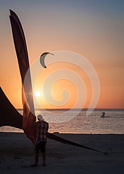 Man on kaytserfing and man on windsurfing at sunset