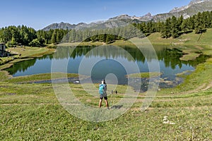 A man keen on trekking makes a stop near Lake Lod to take photos and videos with his smartphone, Aosta Valley, Italy