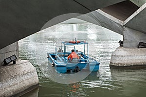 Man keep garbage boat on water under the bridge in Singapore.