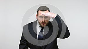 Man keeping palm over head and looking attentively far away.