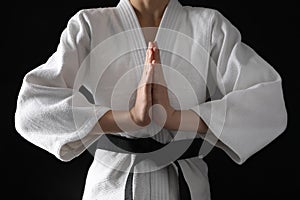 Man in keikogi with black belt on dark background, closeup. Martial arts uniform