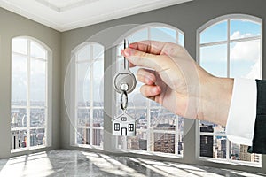 Man with key in hand in modern empty room with concrete floor