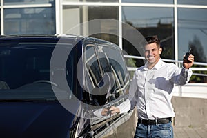 Man with key near car on street. Buying new auto