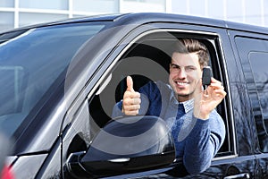 Man with key sitting in car. Buying new auto