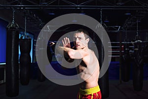 Man kickboxer is practicing kick in a boxing gym