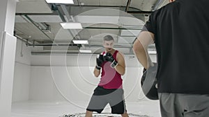 The man kicks the Boxing paw practicing the technique of combat with the instructor