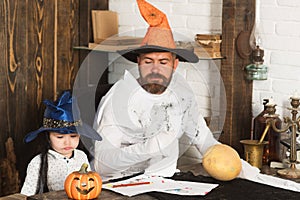 Man and kid with serious faces play with carved pumpkins