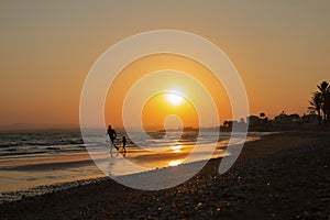 Man and kid silhouette run on the sea shore, on orange sun set backround, vacation evening. Parent and child, Father`s day, Famil