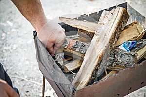 A man kindles a fire in a brazier with matches