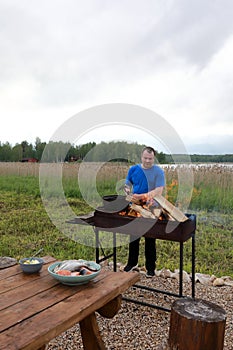 Man kindles firewood in barbecue