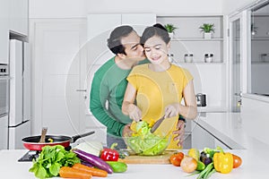 Man kiss his wife while making salad