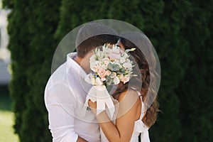 Man kiss woman and hide by bouquet. Wedding day