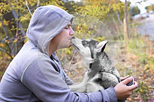 Man kisses  dog puppy of the breed Siberian Husky. dog training and obedience