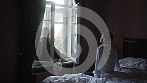 A man kisses a girl in black pajamas sitting on the window