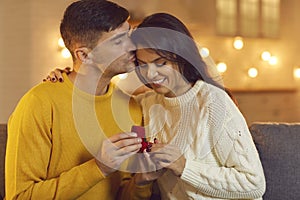 Man kisses a woman on the forehead showing her a wedding ring after a successful marriage proposal.