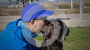 Man kissing his dog in the park