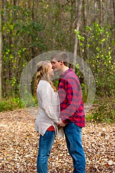 Man kissing his girlfriend on top of the head in the park