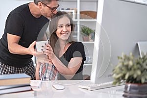 Man kissing his smiling girl at home, drinking coffee in the morning together