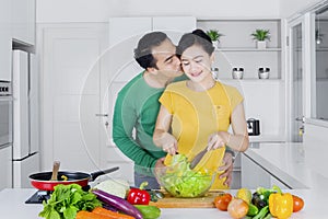 Man kissing his wife while making salad