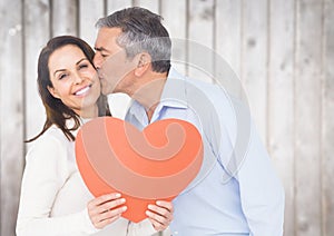 Man kissing woman holding a heart