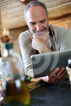 Man in kitchen checking recipe on internet