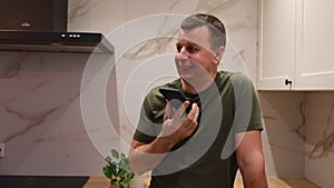 Man in Kitchen Demonstrates Voice Assistant Interaction on Smartphone