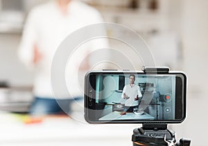 Man on the kitchen filming video.