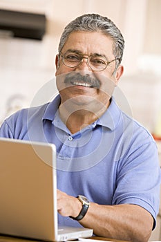 Man in kitchen with laptop smiling