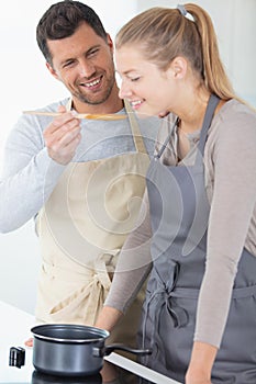 man in kitchen letting woman taste soup