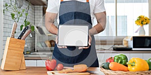 Man in kitchen looking at recipes on tablet