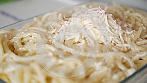 A Man in the Kitchen Prepares a Tray with Macaroni and Grate Cheese