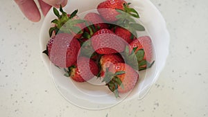 A Man in the Kitchen Selecting and Putting Fresh Strawberries in a Bowl, Preparing a Delicious Vegan Breakfast Full of Vitamins.