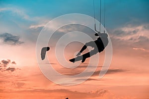 Man kitesurfer athlete jumping at sunset, silhouette at dusk man doing board greab