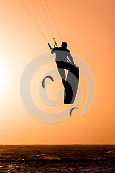 Man kitesurfing jump, kite surfer jumping at sunset on orange background between kites in the ai, kiteboarding at sunset, kitesurf photo