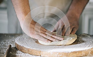 Man kneading and baking homemade pizza dough in the kitchen. Closeup on baker`s hands preparing loaf of bread