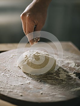 Man kneading and baking homemade pizza dough in the kitchen. Closeup on baker`s hands preparing loaf of bread